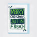 Merry Christmas but in French - white card, green and blue text, sitting on top of a pale blue A6 envelope.