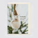 A greeting card featuring a fluffy white snowman ornament with a glittery gold hat hanging in front of blurred evergreen branches. The card text reads, 'Fucksake. I mean, Merry Christmas'