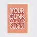 A rectangular greeting card with a peach-pink front and cream envelope. On the card is printed, in bold white text, 'YOUR GONK COLLECTION SUCKS!'