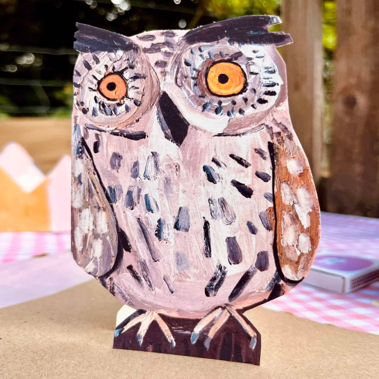 A die-cut Little Owl card with large orange eyes and brown wings, standing on a table.