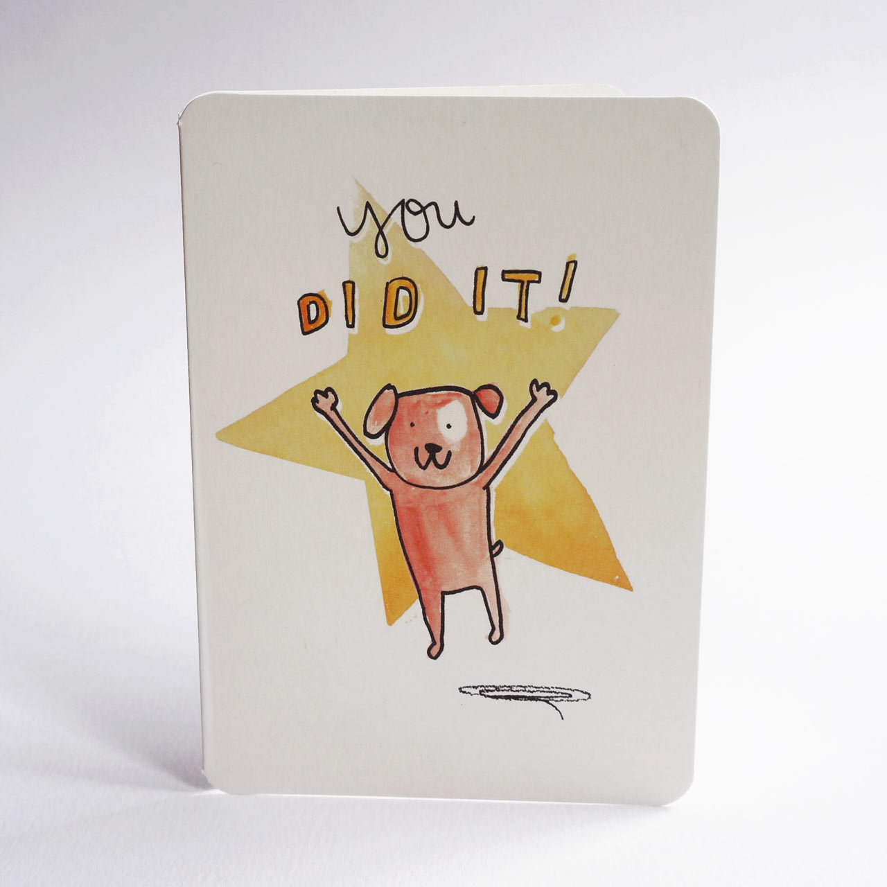 An A6 congratulations card with rounded corners, featuring a hand-drawn illustration of an orange dog jumping in front of a yellow star with the text 'you DID IT!' on a white background.