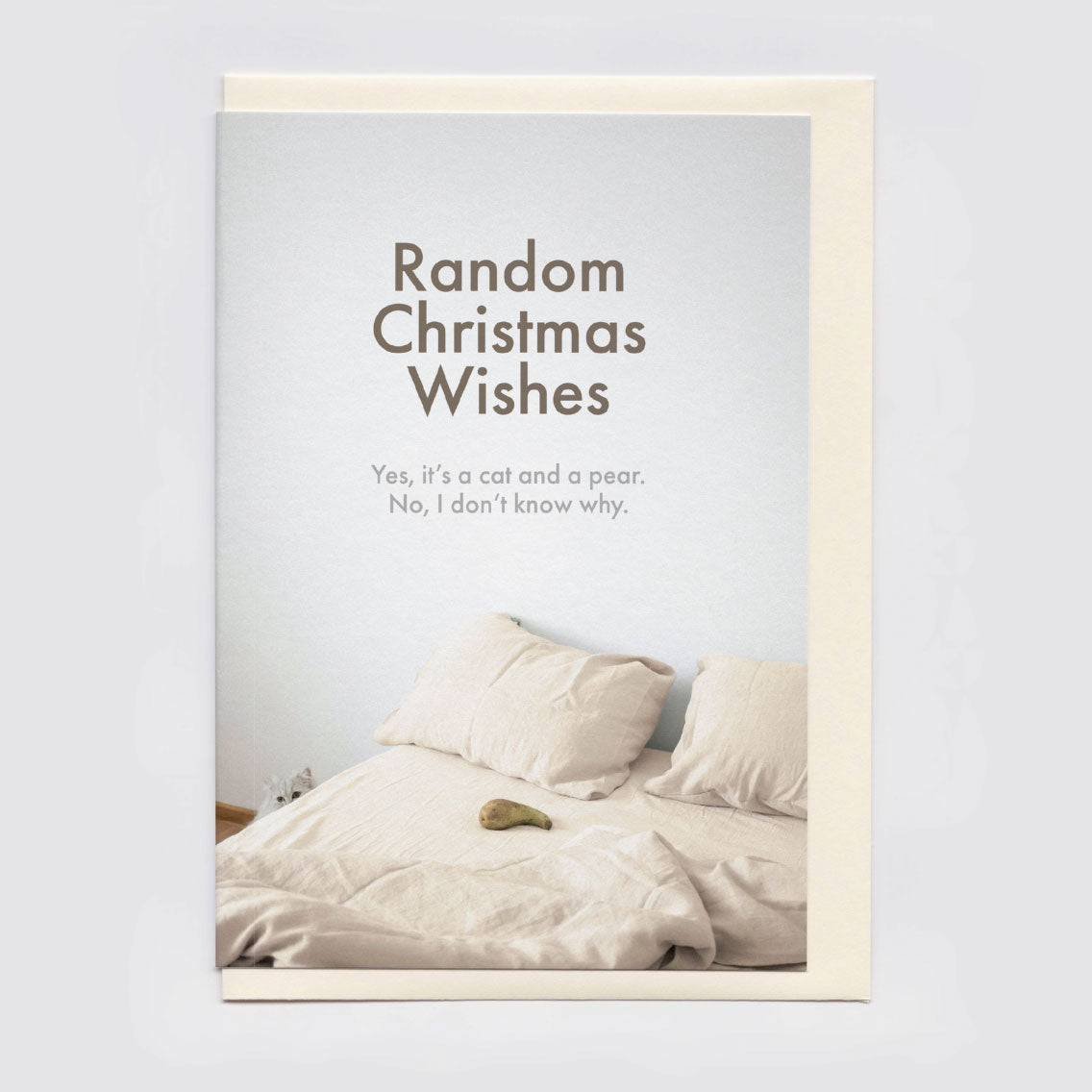 A funny/surreal Christmas card, shown in flat lay, sitting atop a cream envelope.