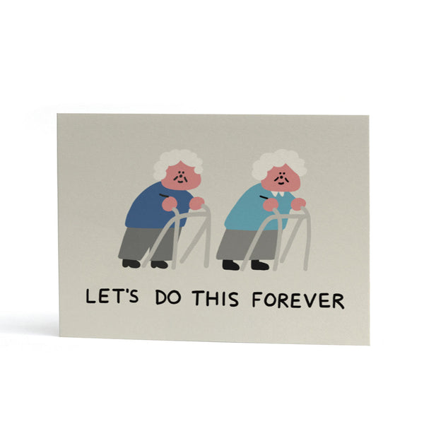An A6 greeting card with a light grey background featuring an illustration of two smiling elderly figures using walkers, with the text 'LET'S DO THIS FOREVER' printed below.
